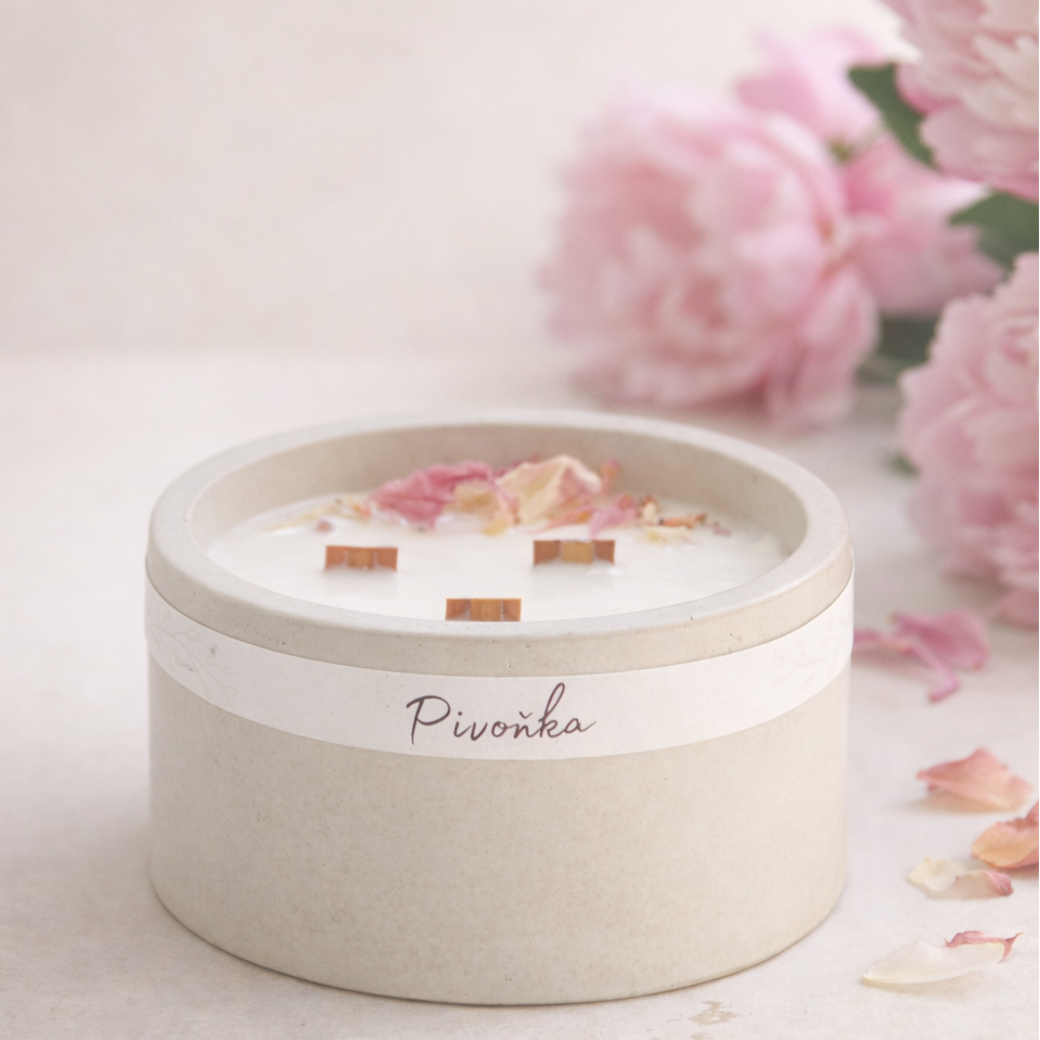 Přírodní ručně vyráběná sójová svíčka Pivoňka v matné keramické dóze s dřevěnými knoty a okvětními lístky pivoňky, aranžovaná v minimalistickém lifestyle stylu na světlém neutrálním pozadí.