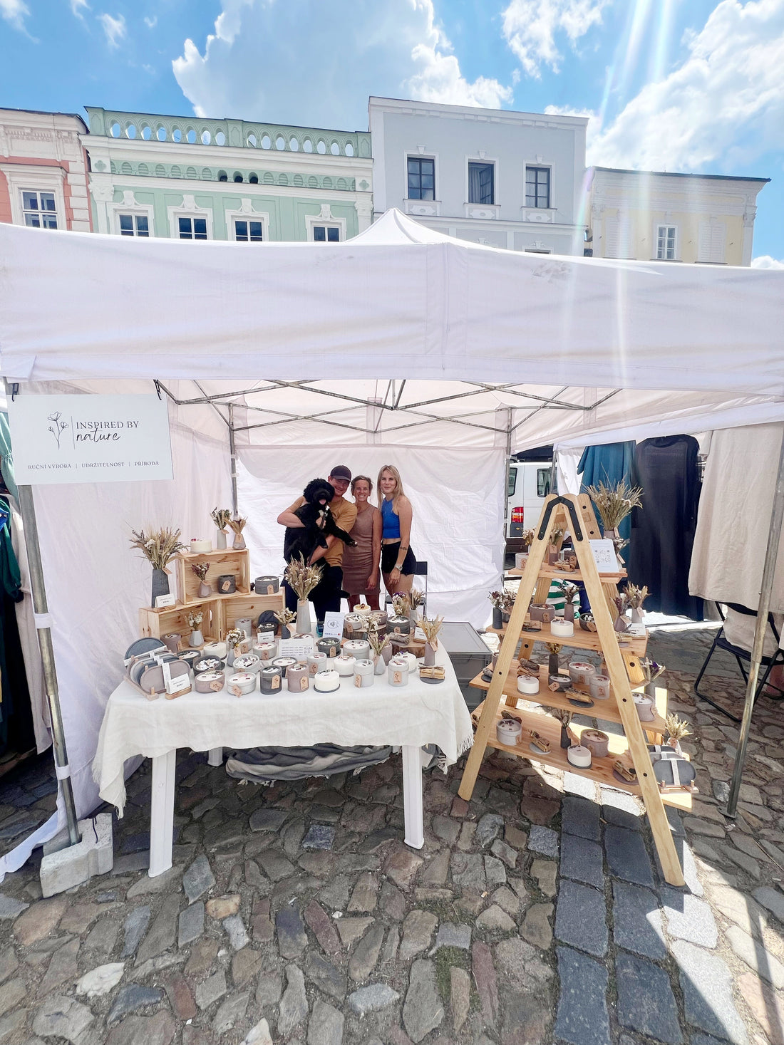 prodavajici stojici na trhu se psem a vystavenymi produkty