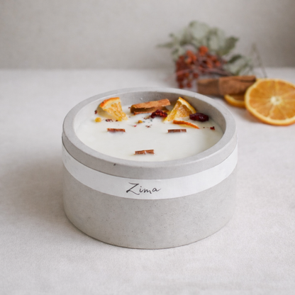 Sójová svicka ve svetle sedem betonu se tremi drvenyxmi knoty s vuni zimy. Zdobena zimnim korenim a pomerancem. V pozadi svicka hori