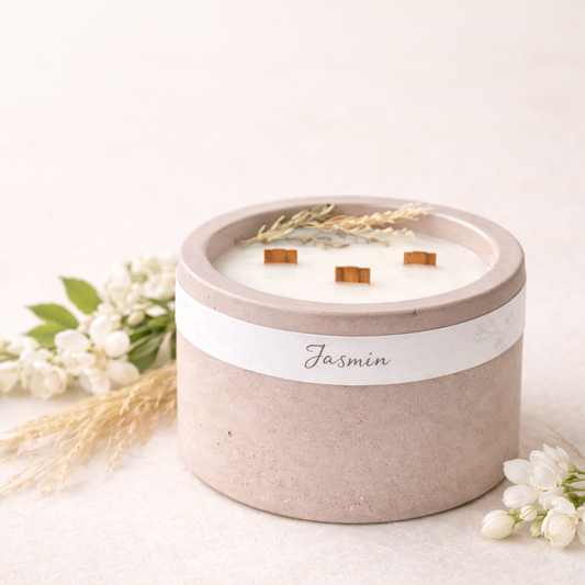 Detail sójové svíčky Jasmín s třemi dřevěnými knoty a jemnými botanickými prvky, v matném betonovém obalu ve starorůžové barvě.