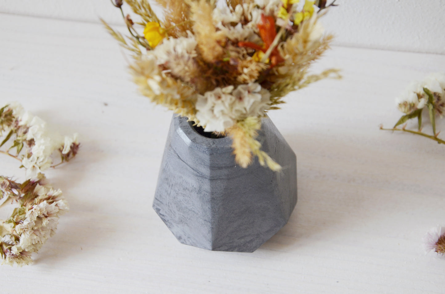concrete vase with dried flowers Květina sušená v betonové vázičce - tmavě šedá diamant. Close up. Point of view from above
