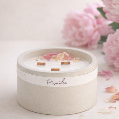 Přírodní ručně vyráběná sójová svíčka Pivoňka v matné keramické dóze s dřevěnými knoty a okvětními lístky pivoňky, aranžovaná v minimalistickém lifestyle stylu na světlém neutrálním pozadí.