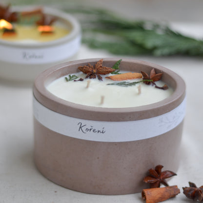 Ručně vyráběná vonná svíčka Koření ve starorůžové betonové mističce se třemi knoty, ozdobená skořicí, badyánem a větvičkami jehličí.