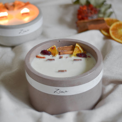 Sójová svicka v betonu se tremi drevenymi knoty s vuni zimy. Zdobena zimnim korenim a pomerancem. V pozadi svicka hori