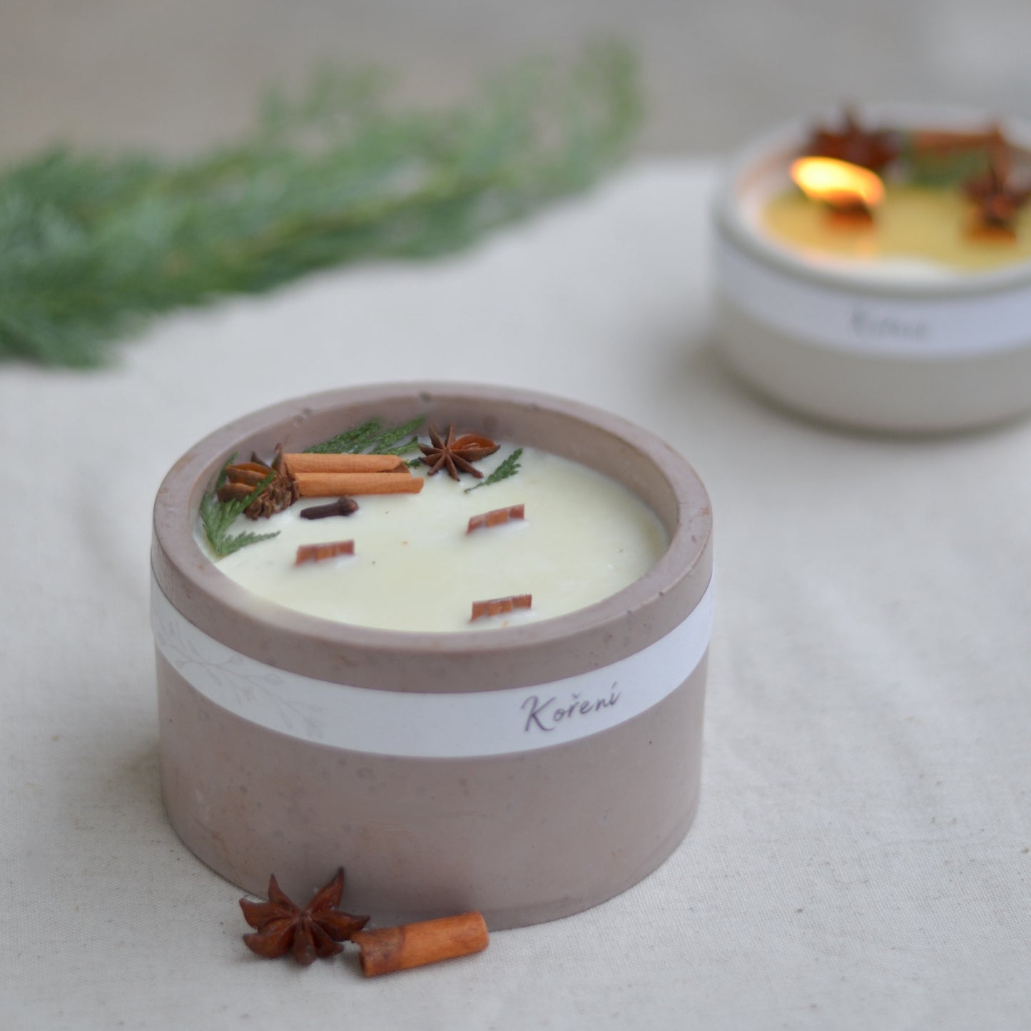 Ručně vyráběná vonná svíčka Koření ve starorůžové betonové mističce se třemi knoty, ozdobená skořicí, badyánem a větvičkami jehličí.