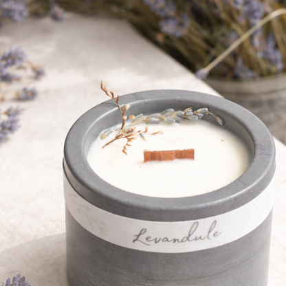 Detail sojové svíčky s dřevěným knotem a sušenou levandulí v tmavém betonovém kalíšku, foceno v měkkém přirozeném světle.