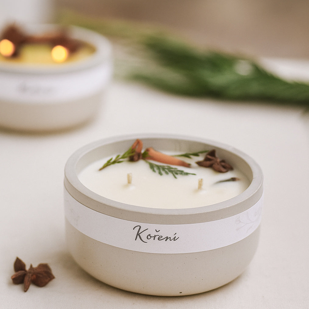 sojova svicka s vuni a zdobenim koreni ve svetle sede betonove nadobce. 