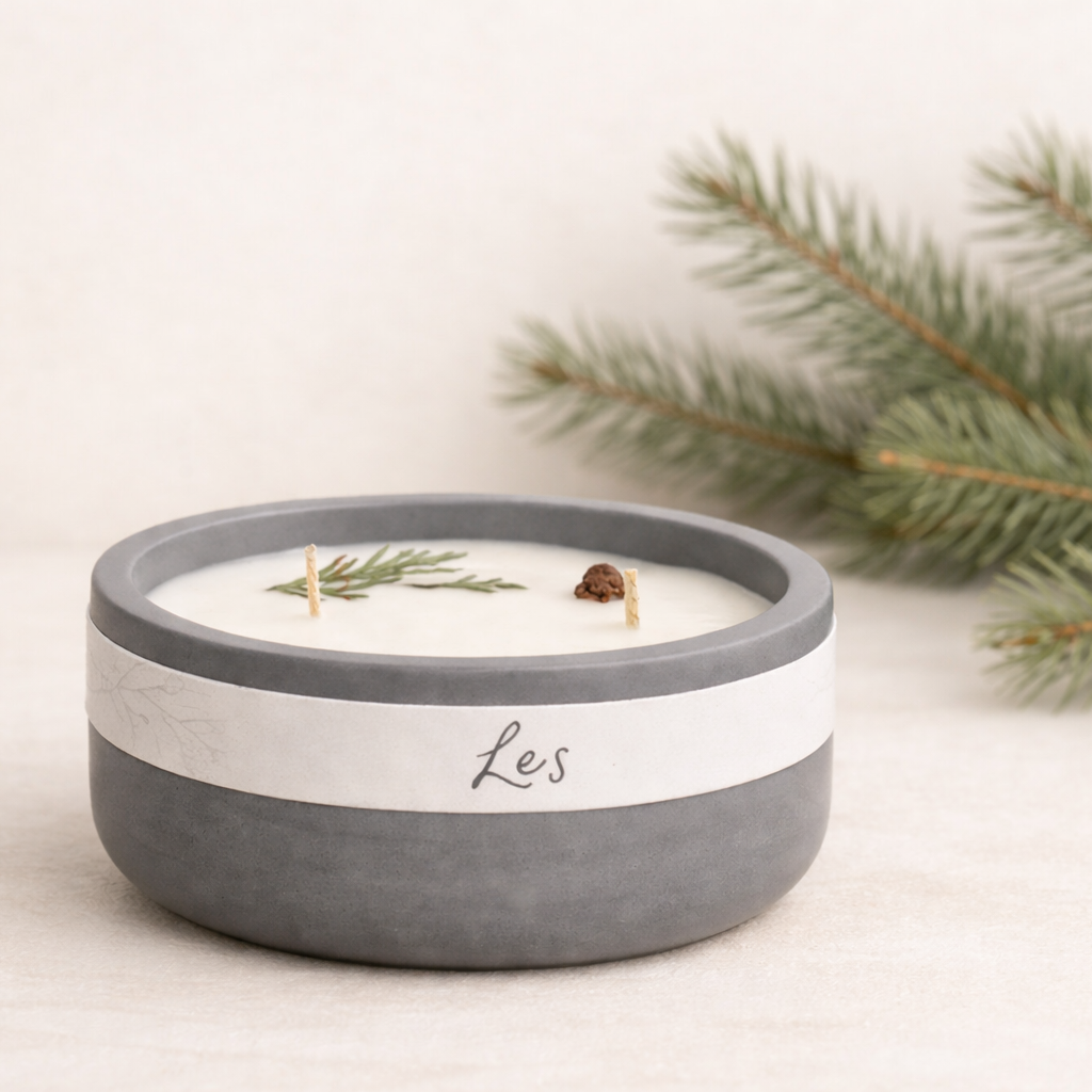 Ručně vyráběná přírodní svíčka Les v matné keramické misce v šedobílém provedení, umístěná na světlém neutrálním podkladu s jemně rozostřenými lesními větvičkami v pozadí.