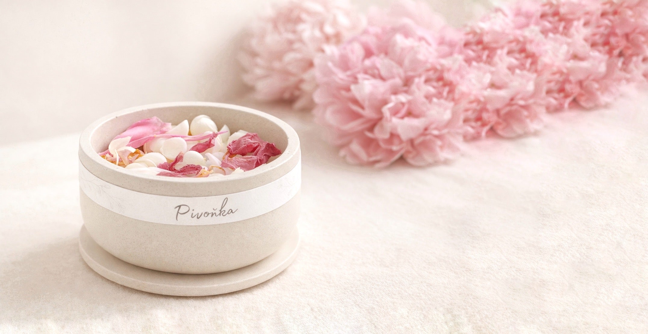 sojove vonne vosky s vuni pivonka v betonove misticce, na svetlem pozadi s ppivonkami v pozadi